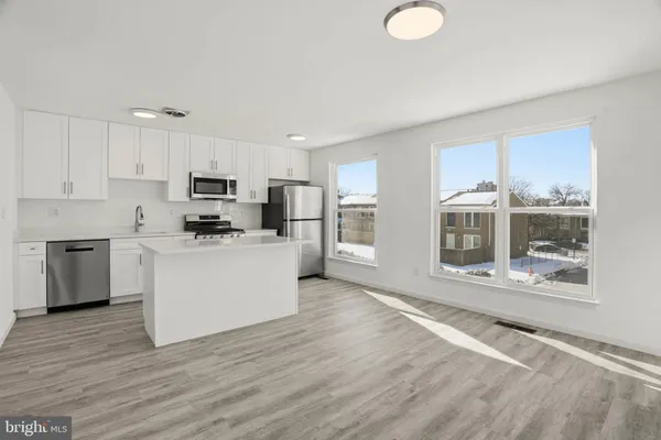 a kitchen with stainless steel appliances a stove top oven a sink a counter space and cabinets