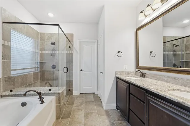 a bathroom with a granite countertop tub sink and mirror