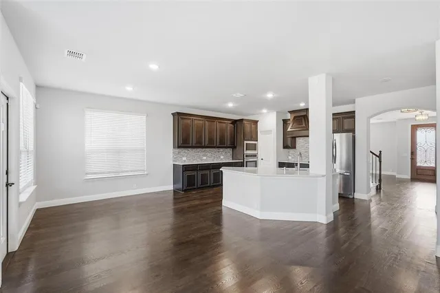 a view of a big room with wooden floor and windows