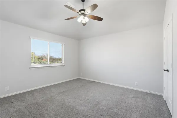 an empty room with a window and a ceiling fan