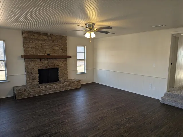 an empty room with wooden floor fireplace and windows