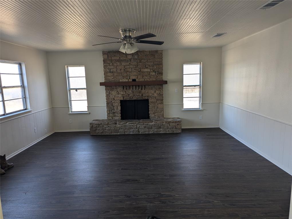 502 East Baker Street Hamilton, TX 76531 - Photo 30 of 37 an empty room with wooden floor fireplace and windows