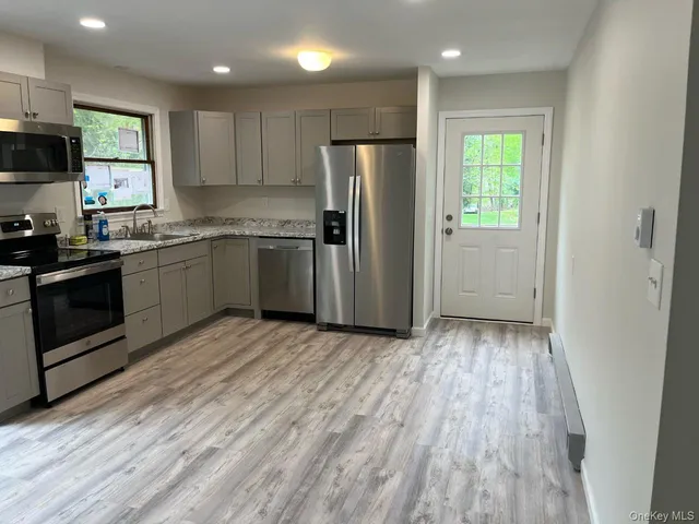 a kitchen with a refrigerator a stove top oven a sink and dishwasher with wooden floor