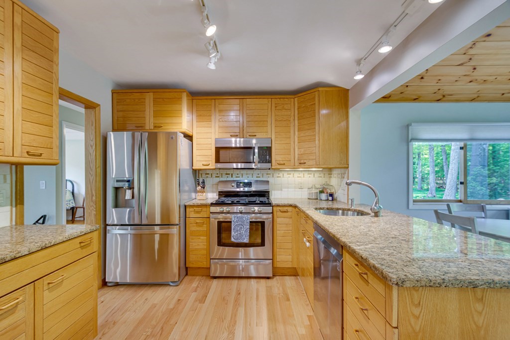 65 Angelica Drive Framingham, MA 01701 - Photo 16 of 34 a kitchen with stainless steel appliances granite countertop a refrigerator a sink dishwasher a stove with wooden floor and cabinets