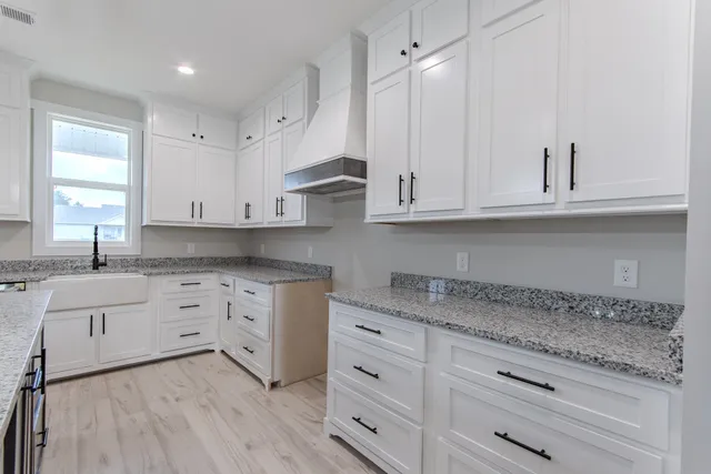 a kitchen with granite countertop white cabinets white appliances and a sink