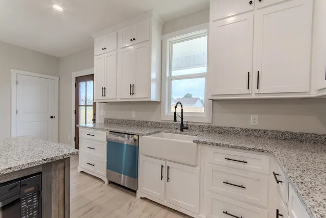 a kitchen with granite countertop cabinets stainless steel appliances a sink and wooden floor
