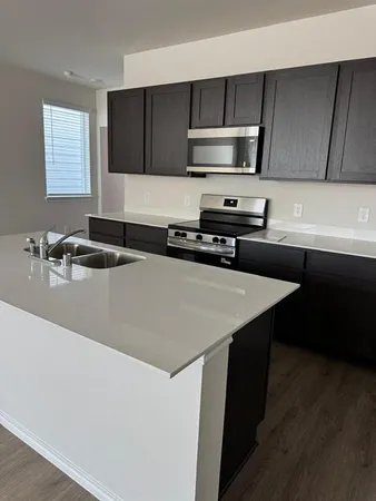 a kitchen with stainless steel appliances a sink a stove a microwave a sink a refrigerator and cabinets