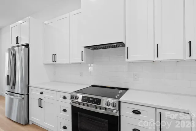 a kitchen with stainless steel appliances white cabinets and a refrigerator