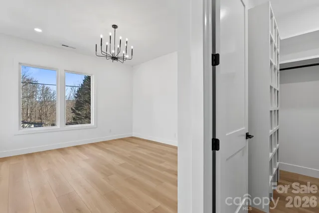 a view of empty room with window and wooden floor