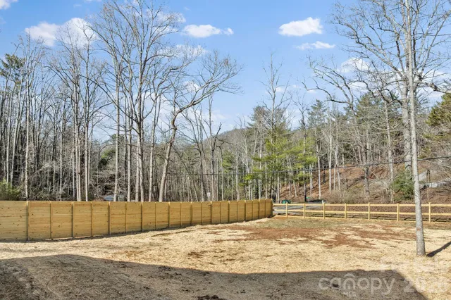 a view of a house with a large tree and wooden fence