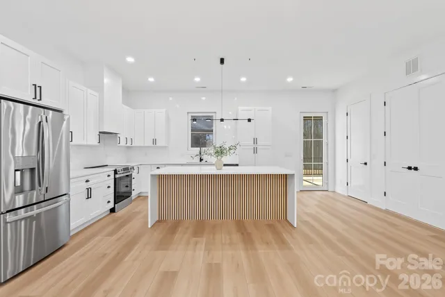 a large white kitchen with kitchen island a sink a center island stainless steel appliances and a cabinets