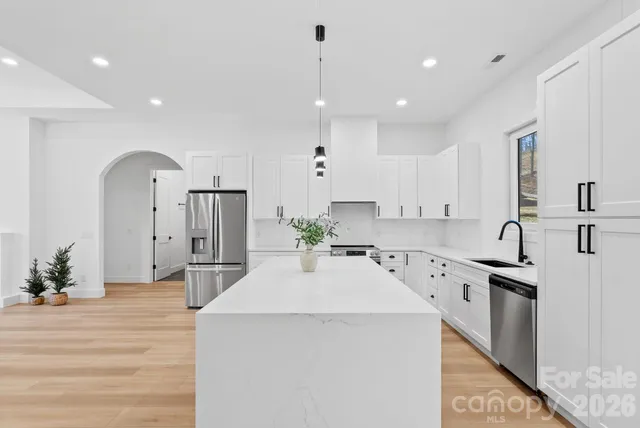 a kitchen with stainless steel appliances kitchen island granite countertop a sink a stove and a refrigerator