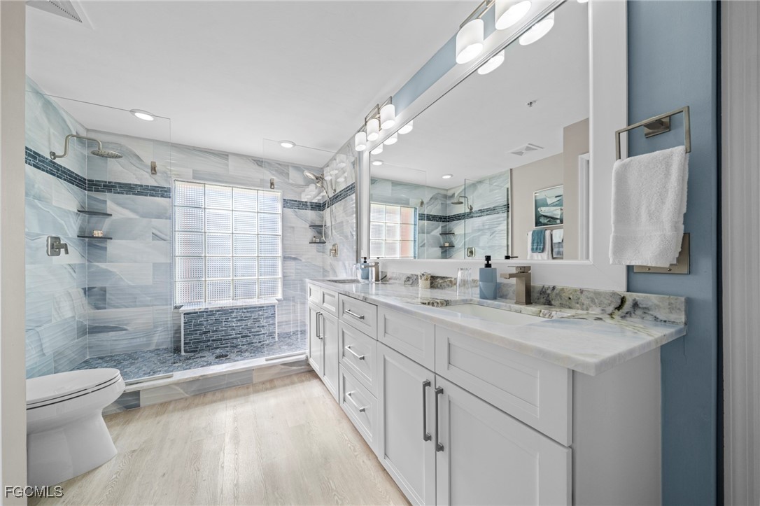 14813 Laguna Drive, Unit 301 Fort Myers, FL 33908 - Photo 28 of 50 a bathroom with a granite countertop sink a toilet a mirror and shower