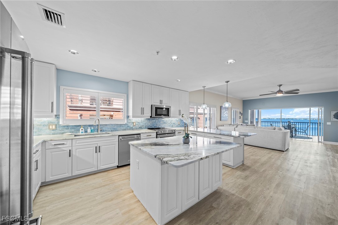 14813 Laguna Drive, Unit 301 Fort Myers, FL 33908 - Photo 4 of 50 a large kitchen with kitchen island a sink a stove a center island and living room view