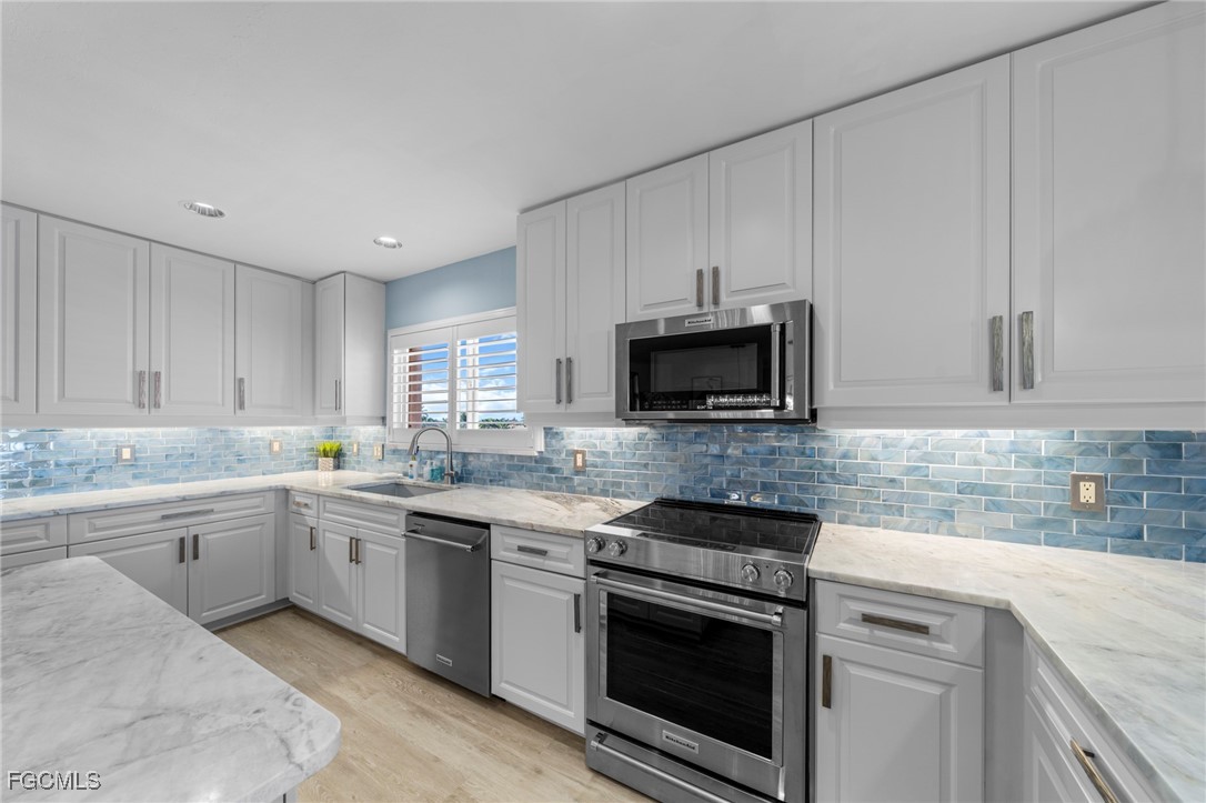 14813 Laguna Drive, Unit 301 Fort Myers, FL 33908 - Photo 6 of 50 a kitchen with white cabinets stainless steel appliances and sink