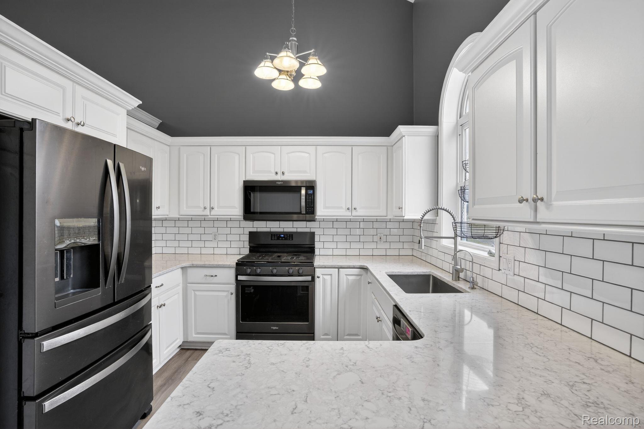 9055 Hegel Road Grand Blanc, MI 48439 - Photo 26 of 62 Kitchen featuring white cabinetry, white subway tile backsplash, stainless steel appliances, and light-toned countertops