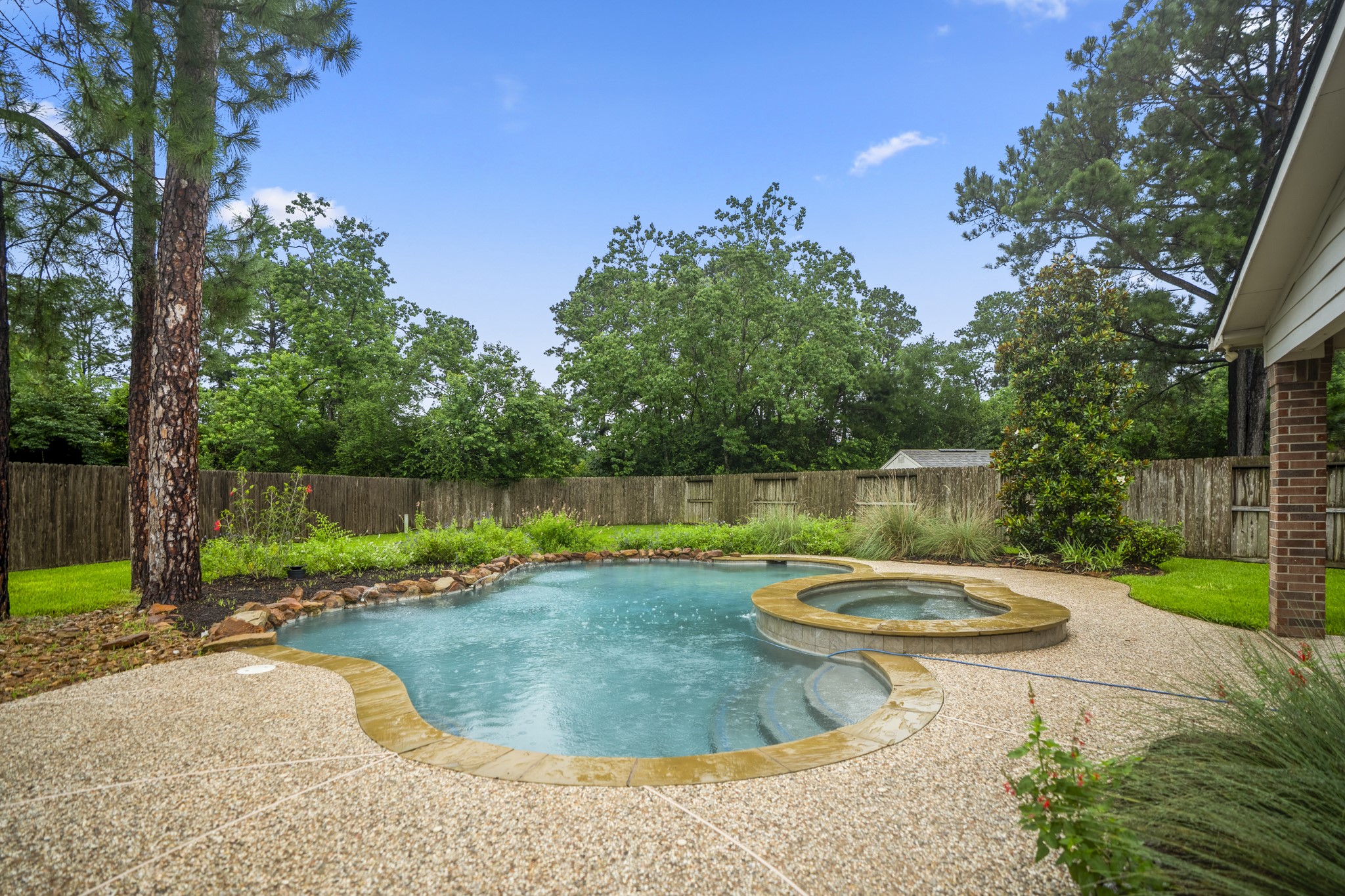 6311 Sparrows Glen Lane Spring, TX 77379 - Photo 34 of 50 A closer look at the pool + spa shows the backyard’s staycation feel from another angle, with curved water features, mature trees beyond the fence, and no rear neighbors adding to the sense of space and retreat.