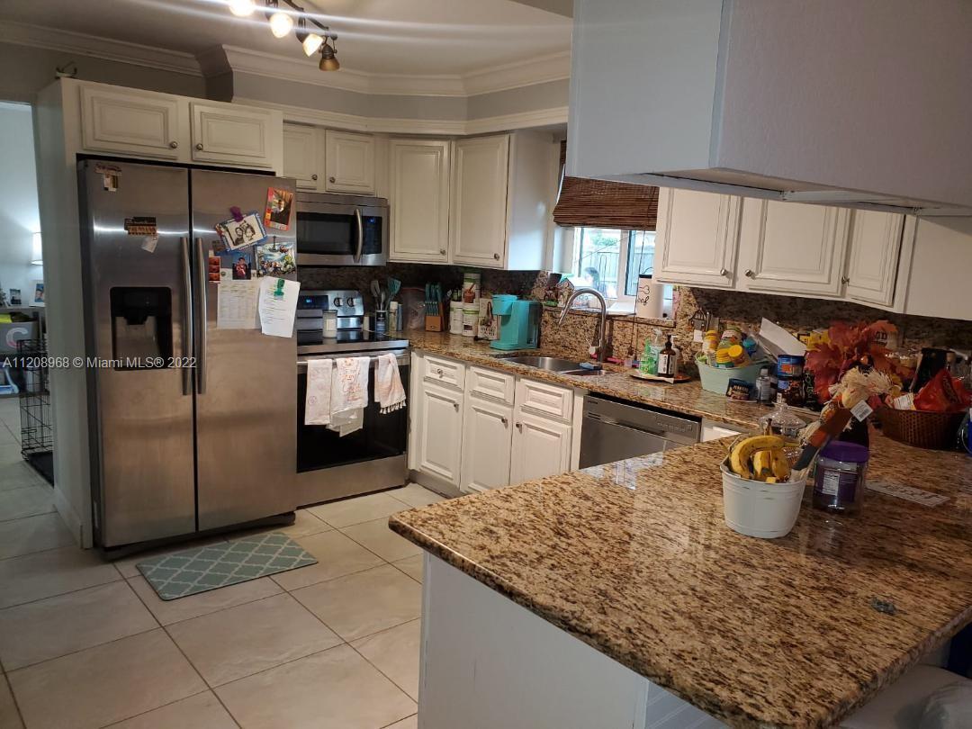 10650 Eland Street Boca Raton, FL 33428 - Photo 6 of 17 a kitchen with stainless steel appliances kitchen island granite countertop a sink refrigerator and cabinets
