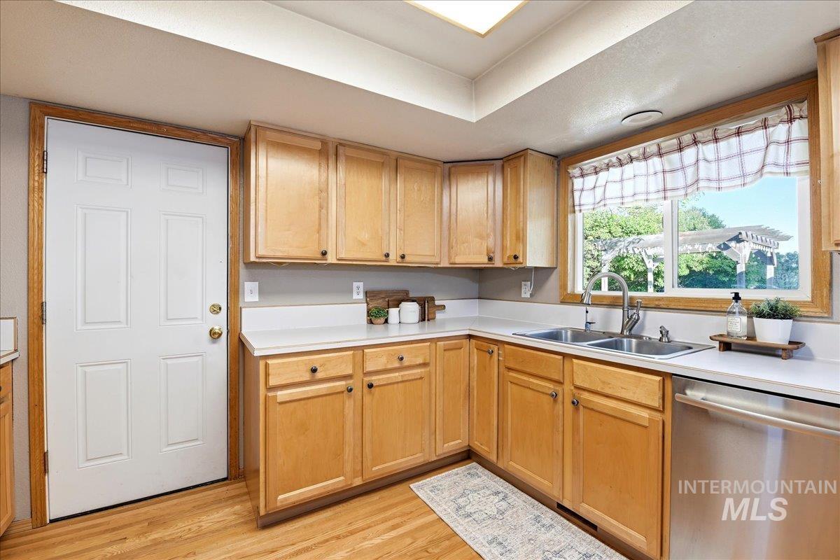 11842 Tioga Street Boise, ID 83709 - Photo 12 of 50 Kitchen featuring wood-finish flooring, light-toned cabinetry with dark hardware, solid surface countertops, and a double basin sink