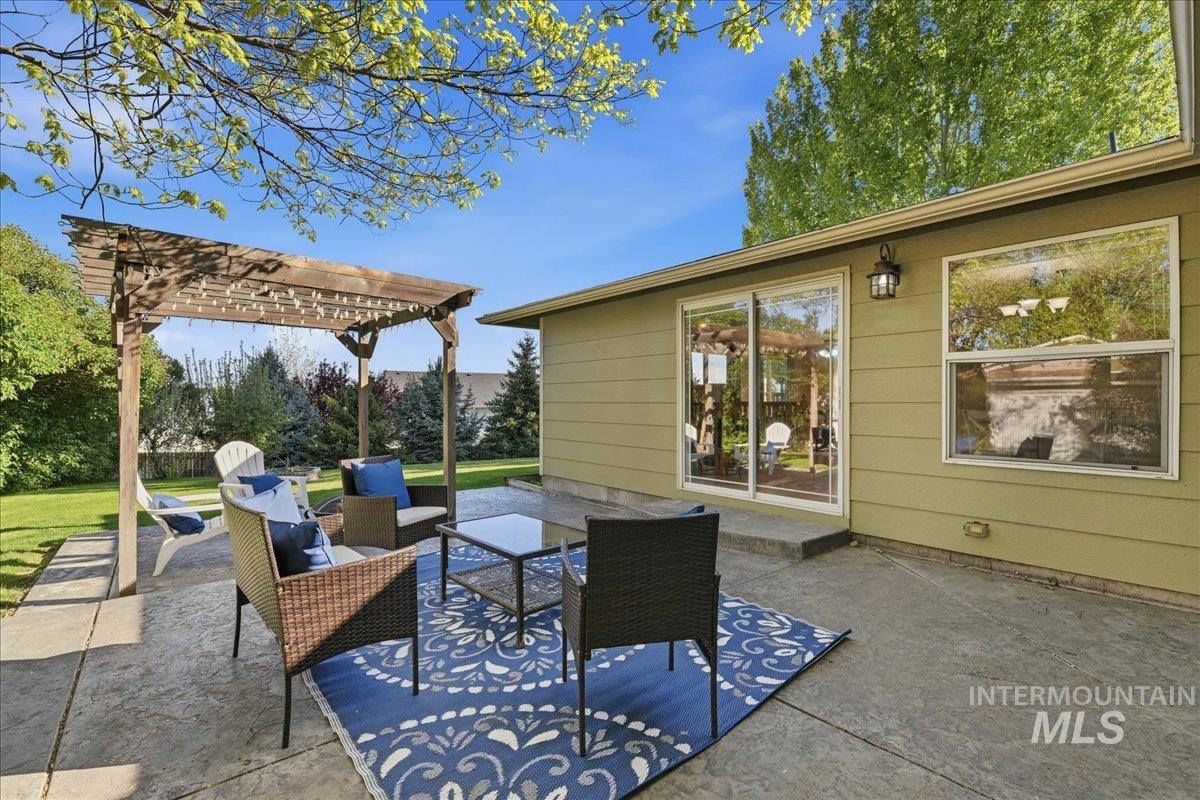 11842 Tioga Street Boise, ID 83709 - Photo 16 of 50 Stamped concrete patio featuring a wooden pergola with string lights, sliding glass doors, and an exterior wall lantern