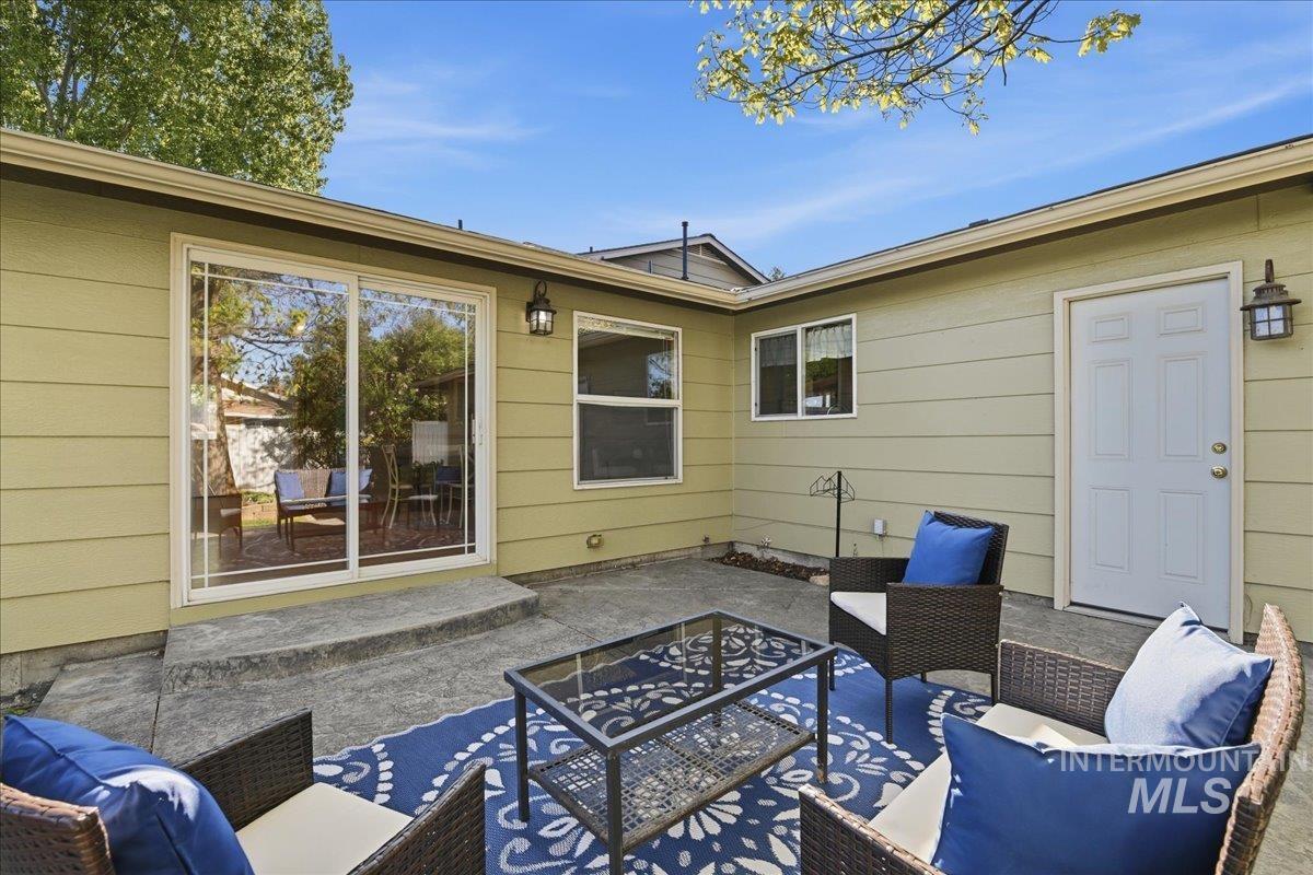 11842 Tioga Street Boise, ID 83709 - Photo 18 of 50 Exterior patio featuring concrete flooring, a sliding glass door, a paneled exterior door, horizontal siding, and exterior lighting fixtures