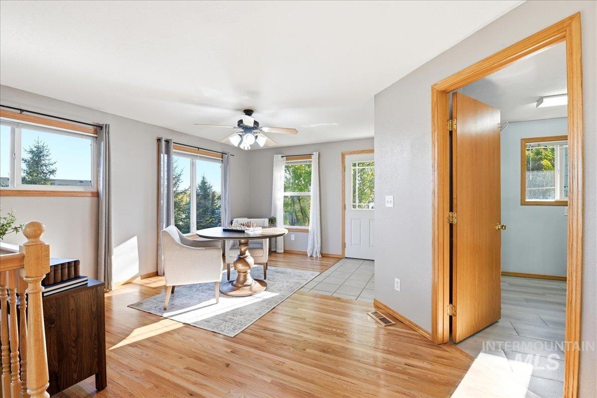 11842 Tioga Street Boise, ID 83709 - Photo 19 of 50 Hardwood flooring extends throughout this sunlit interior space, featuring multiple windows with natural light, a ceiling fan, and a tiled entry area