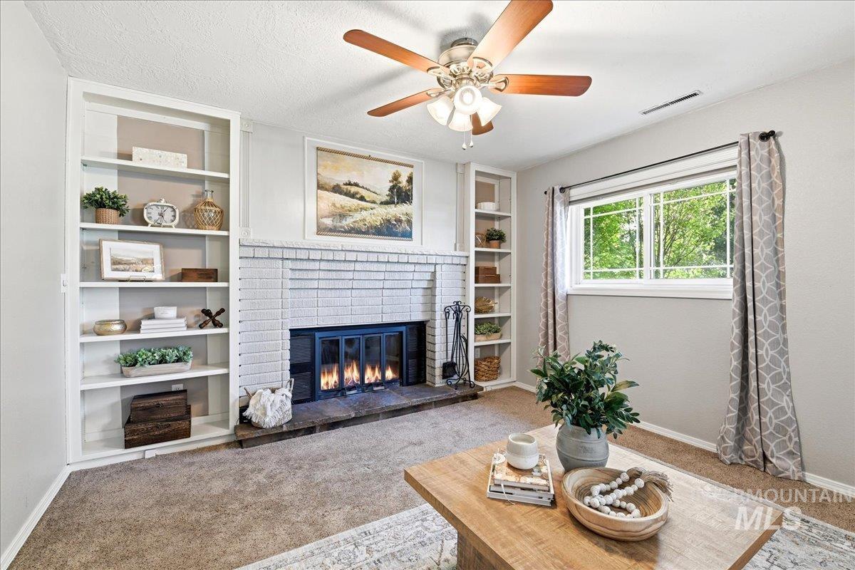 11842 Tioga Street Boise, ID 83709 - Photo 22 of 50 Brick fireplace with a stone hearth, flanked by built-in shelving, under a ceiling fan with wood-finish blades