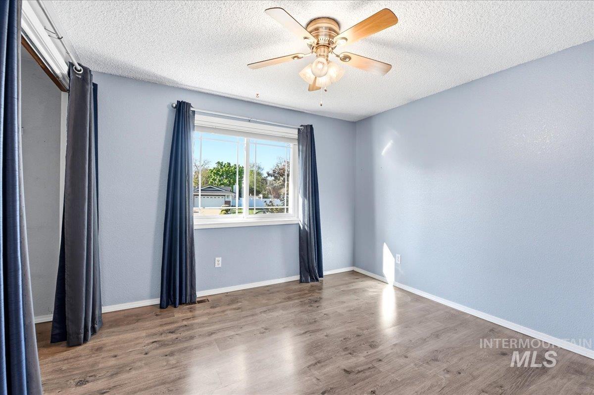 11842 Tioga Street Boise, ID 83709 - Photo 24 of 50 Room featuring a large picture window, wood-finish flooring, a ceiling fan with light fixture, and light blue walls