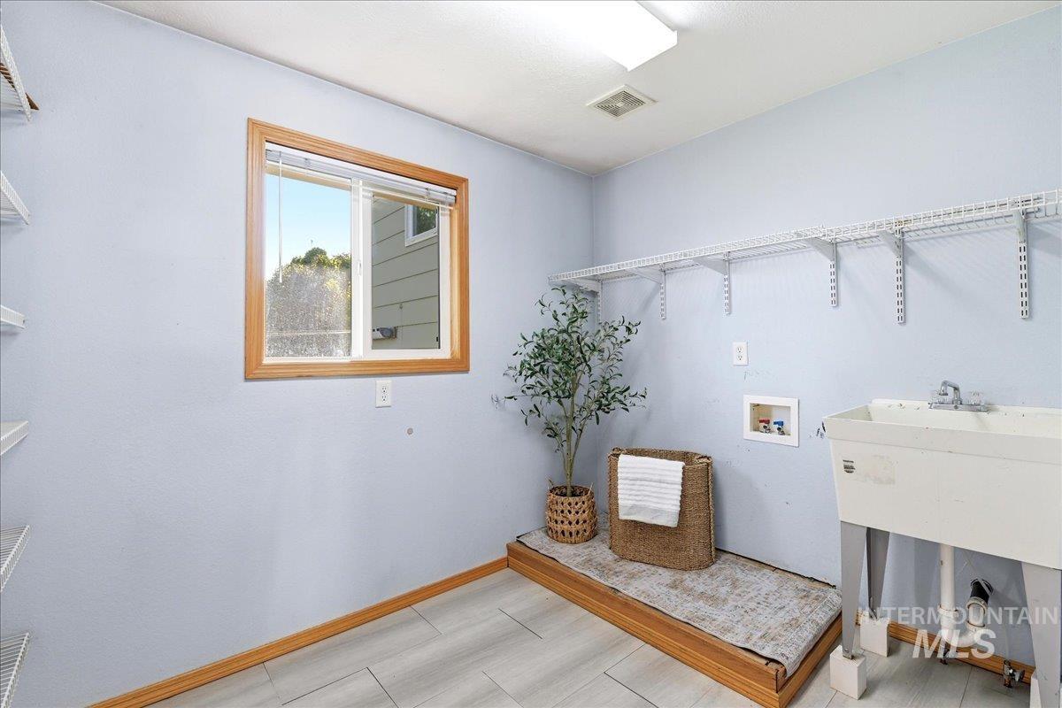 11842 Tioga Street Boise, ID 83709 - Photo 26 of 50 Laundry room featuring a utility sink, wood-finish flooring, and a single window with wood trim