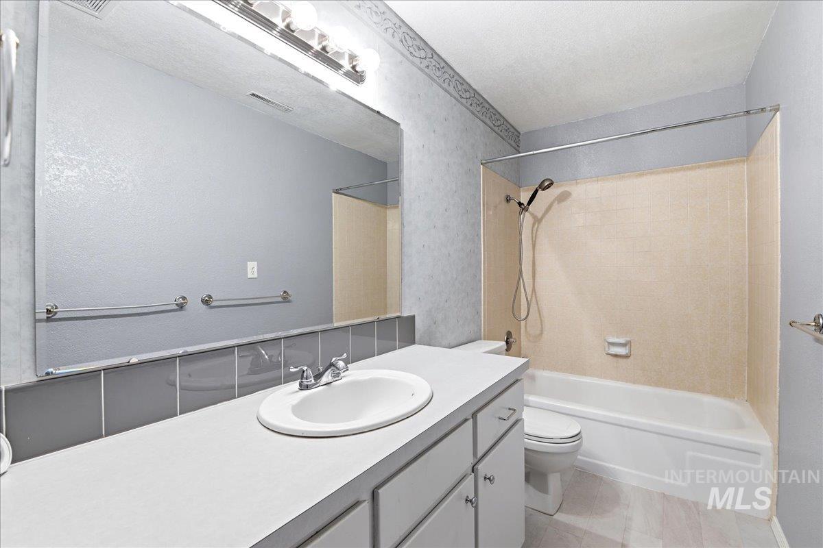 11842 Tioga Street Boise, ID 83709 - Photo 28 of 50 Bathroom featuring a vanity with an integrated sink, a large wall-mounted mirror, and a full-size bathtub with an overhead shower