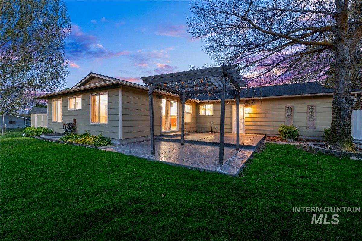 11842 Tioga Street Boise, ID 83709 - Photo 33 of 50 Expansive backyard featuring a large stamped concrete patio, a pergola with string lighting, a mature shade tree, and a manicured lawn