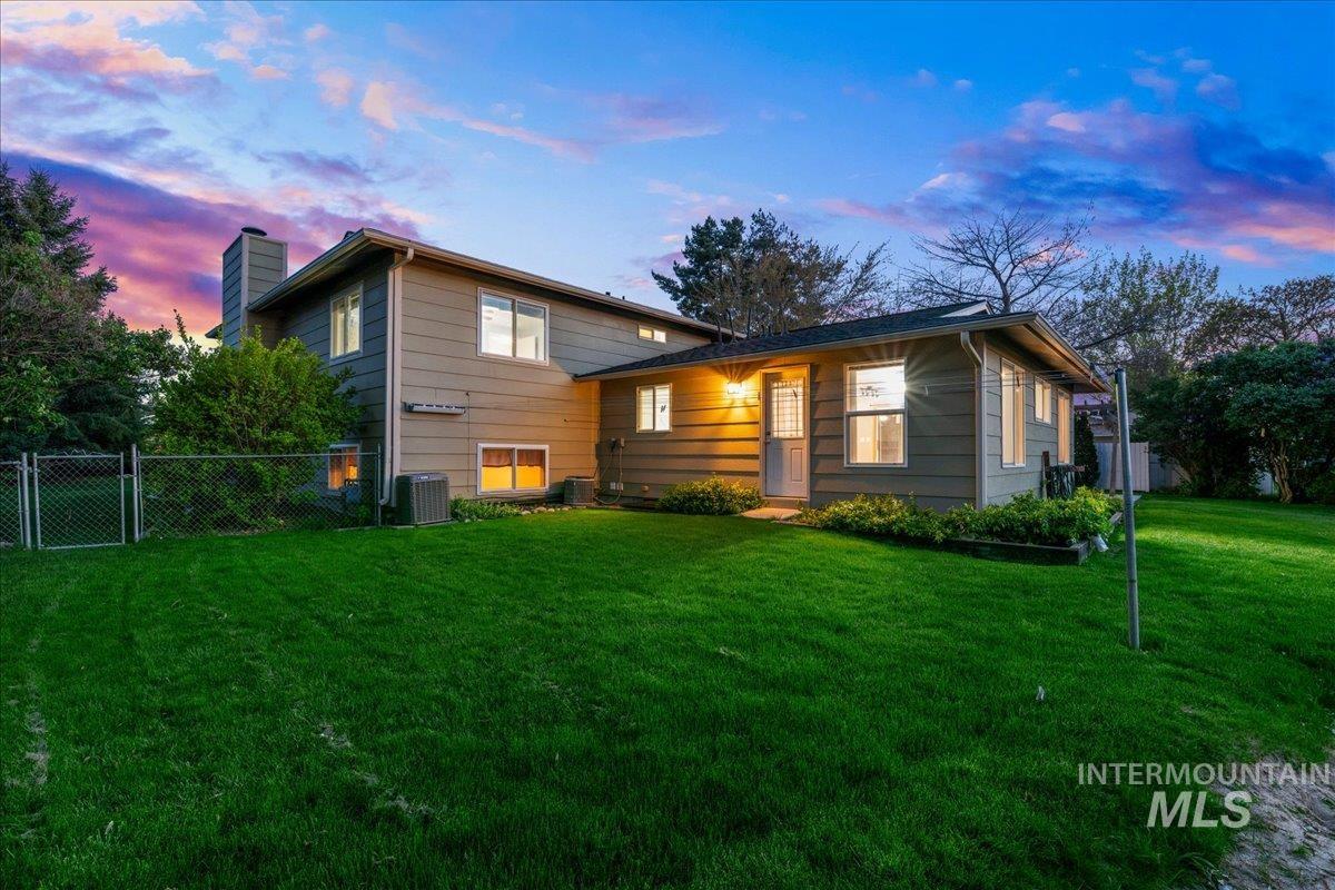 11842 Tioga Street Boise, ID 83709 - Photo 34 of 50 Spacious backyard with a vibrant green lawn, mature perimeter trees, and a chain link fence