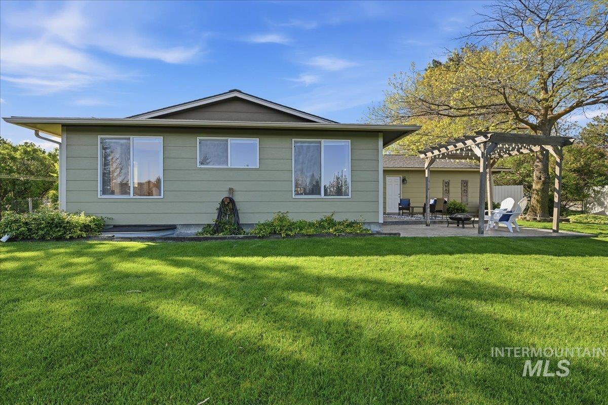 11842 Tioga Street Boise, ID 83709 - Photo 36 of 50 Expansive backyard featuring a manicured lawn, a large paver patio, a wooden pergola, and established perimeter landscaping