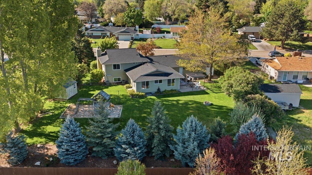 11842 Tioga Street Boise, ID 83709 - Photo 38 of 50 Expansive backyard featuring a manicured lawn, mature trees, and a wooden privacy fence