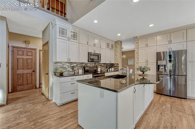 Updated kitchen with quartz countertops, a tile backsplash, black stainless steel appliances and an abundance of cabinet storage