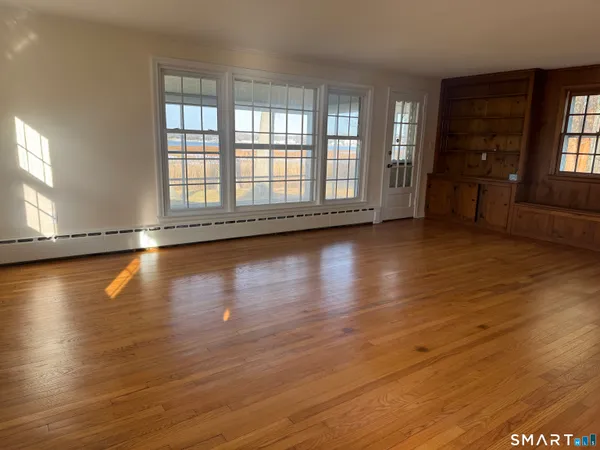 an empty room with wooden floor and windows