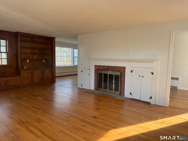 an empty room with wooden floor fireplace and windows
