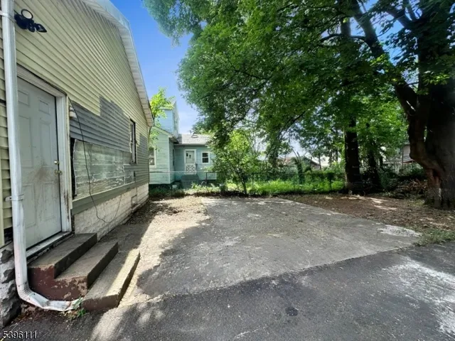 a view of backyard with large trees and plants