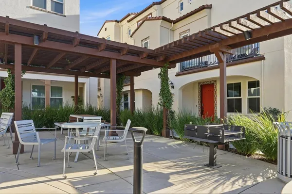 a view of a patio with table and chairs potted plants and floor to ceiling window