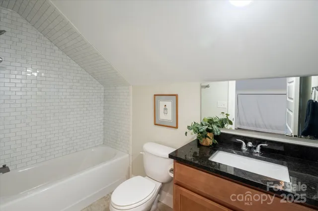 a bathroom with a granite countertop sink a toilet and mirror