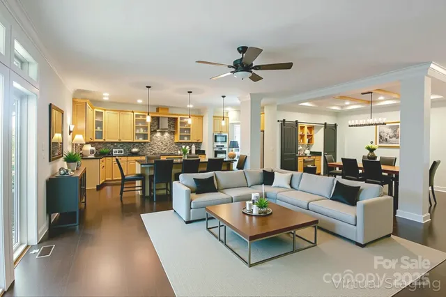 a living room with furniture kitchen view and a large window