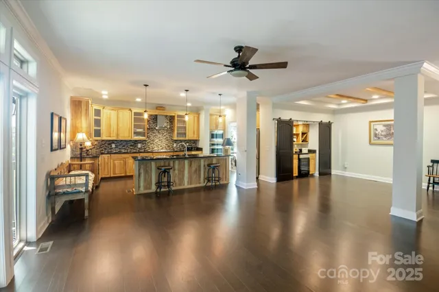 a living room with couches and kitchen view with wooden floor
