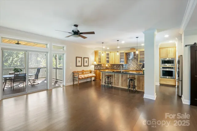 a view of a living room kitchen with stainless steel appliances wooden floor and a large window