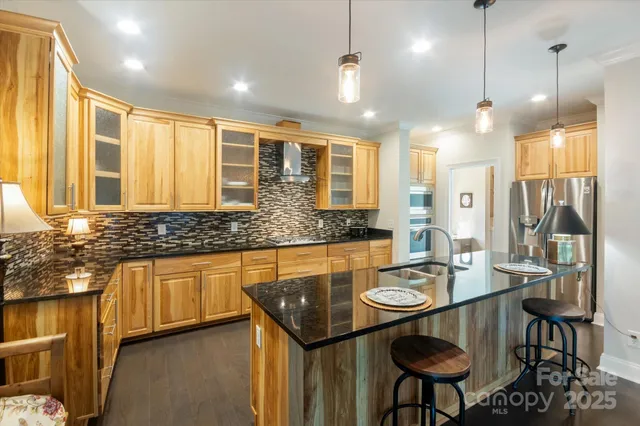 a open kitchen with stainless steel appliances granite countertop a stove a sink a refrigerator a dining table and chairs with wooden floor