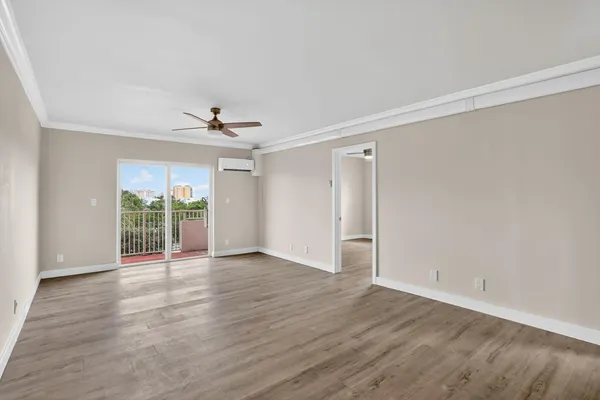 a view of an empty room with wooden floor and a window