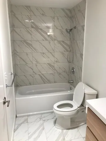 a white toilet sitting next to a bath tub and a shower