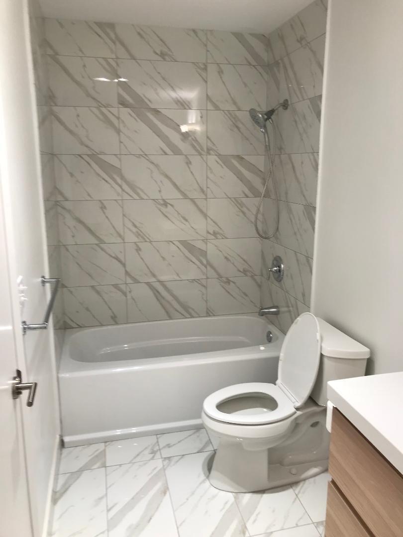 1387 High Point Way Northwest, Unit B Delray Beach, FL 33445 - Photo 12 of 16 a white toilet sitting next to a bath tub and a shower