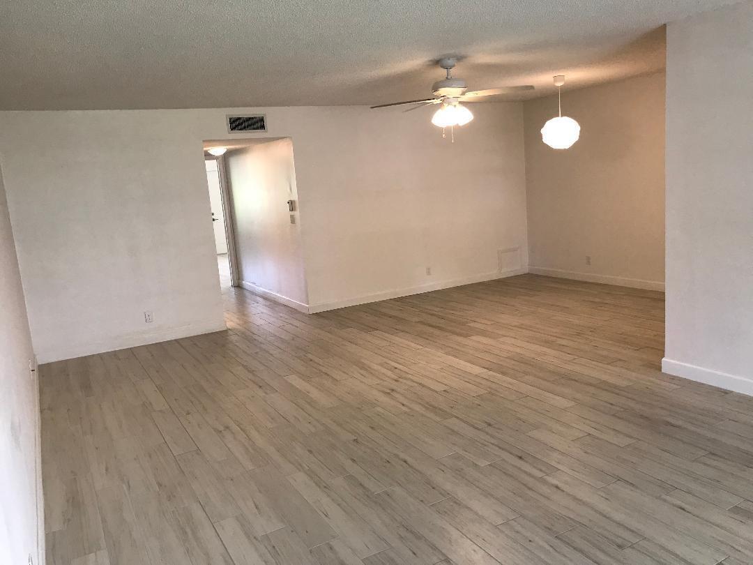 1387 High Point Way Northwest, Unit B Delray Beach, FL 33445 - Photo 3 of 16 an empty room with wooden floor and windows