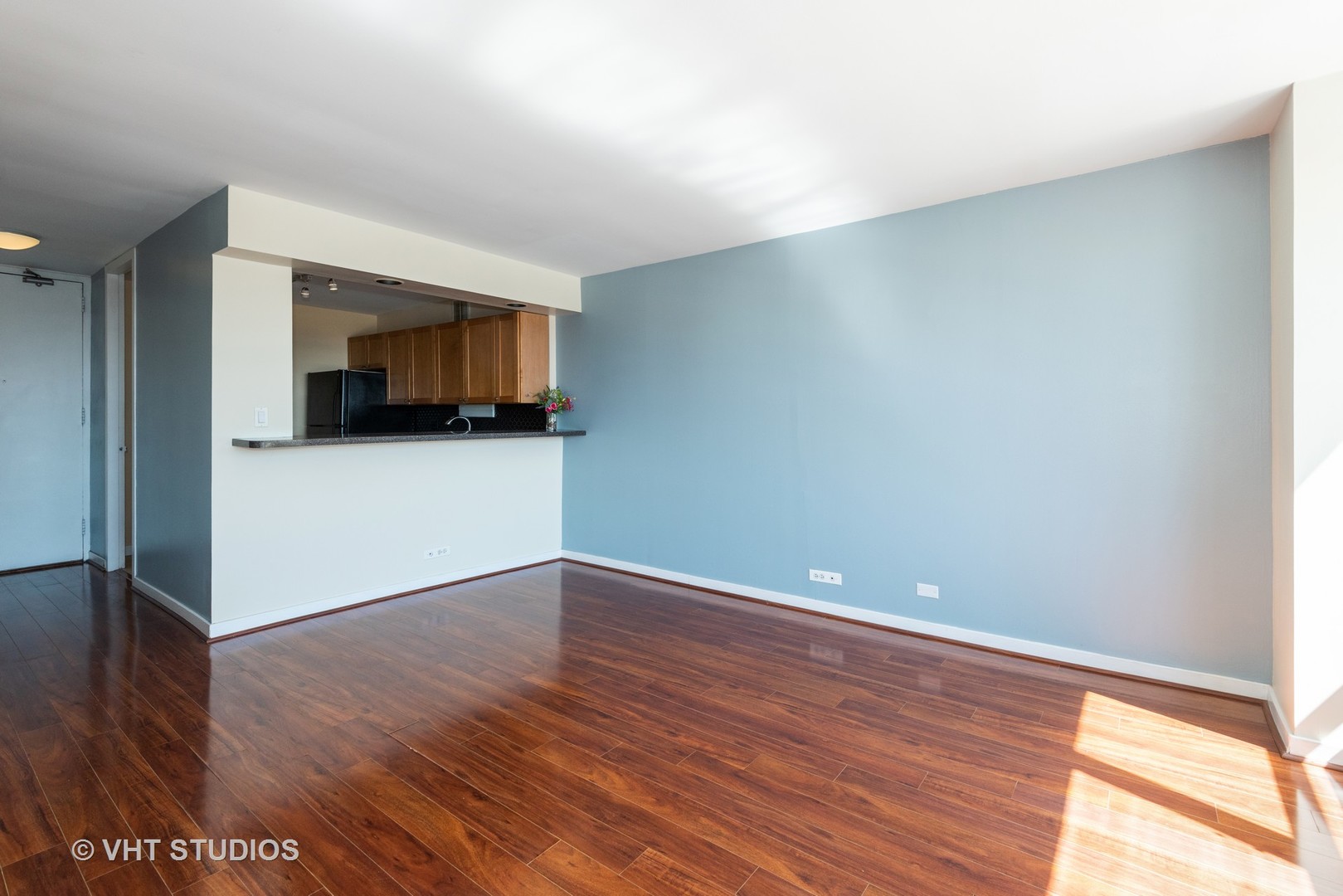 655 West Irving Park Road, Unit 1109 Chicago, IL 60613 - Photo 10 of 29 a view of an empty room with wooden floor and kitchen