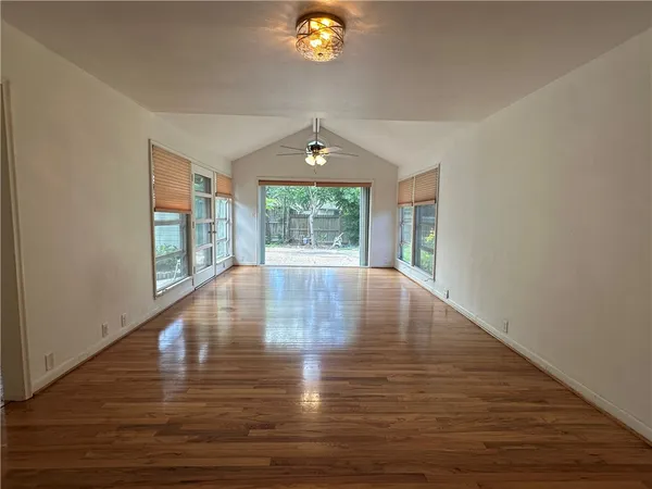 a view of an empty room with window and wooden floor